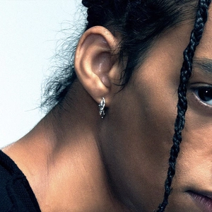 Unisex silver thorn hoop earring with artistic twisted metal design on model ear