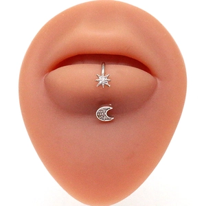 Lip piercing studs with star and moon designs on a silicone lip model display