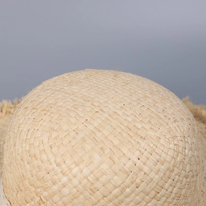 Detailed macro view of the hand-woven natural straw texture on a dome-shaped sun hat