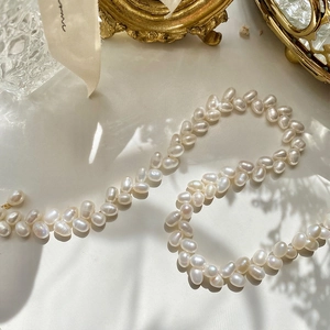 Elegant gold plated leaf pearl necklace with white oval pearls in an S-shaped composition