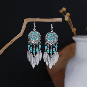 Detail of bohemian drop earrings with turquoise beads hanging on a rustic wooden branch