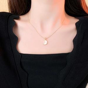 Détail du collier croissant de lune doré avec nacre blanche porté par un mannequin