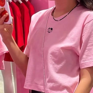 Close-up of a pink t-shirt with a black heart graphic and minimalist beaded necklace