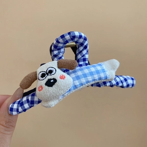 Gros plan d'une pince à cheveux à carreaux bleus avec une figurine de chien en peluche