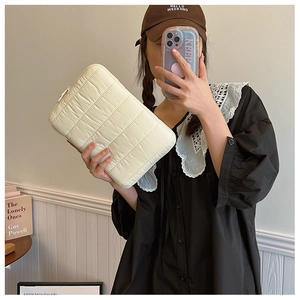 Quilted cream laptop sleeve with horizontal stitching and zipper closure detail
