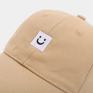 Détail de la casquette de baseball en coton kaki avec broderie carrée blanche sourire