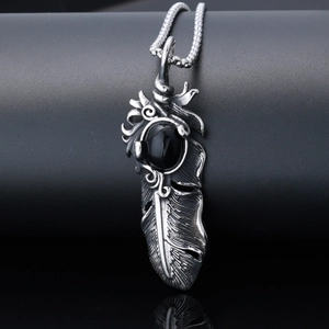 Detailed shot of a vintage stainless steel feather pendant with an oval black gemstone