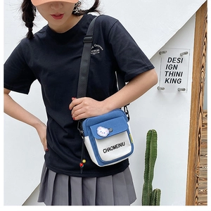 Side view of a blue and white canvas crossbody bag featuring a cute bear patch and beads