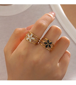 Detail of 18K gold plated flower rings in black and white enamel on a hand