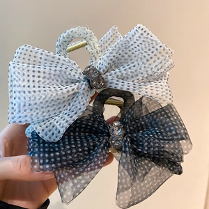 Detailed macro shot of polka dot mesh bow hair clips with sparkling rhinestone centerpieces