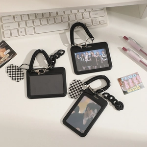 Black ID card holders with spring coils and checkerboard charms on a desk