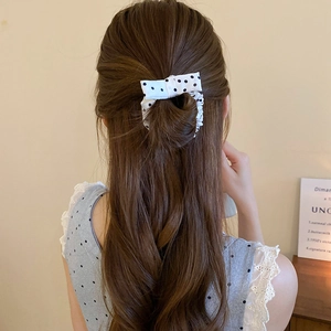 Close-up of a cream hair scrunchie with black polka dots and a bow on hair