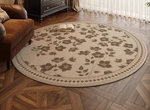 Detail of round floral carpet with geometric border on vintage wood flooring in a living room