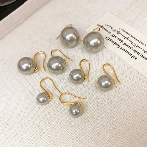 Flat lay of four pairs of elegant gray pearl earrings with 18K gold-plated hooks on fabric