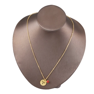 Detailed view of Aries zodiac necklace in gold with red birthstone on a mannequin