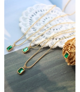 Detail of emerald green zircon pendant on gold beaded chain with vintage floral decor