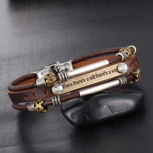 Détail d'un bracelet multicouche en cuir avec plaque gravée sur une pierre noire