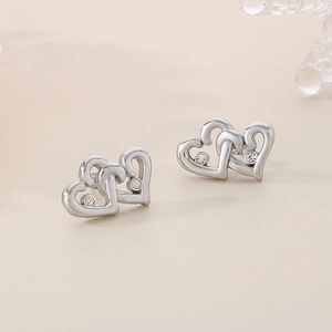 Macro detail of intertwined heart stud earrings with sparkling crystal accents in silver