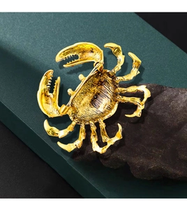 Macro detail of a golden alloy crab brooch placed on a textured dark rock background