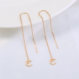 Detail of elegant gold tassel drop earrings with moon and star zircon pendants on silk
