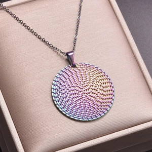 Detail view of rainbow iridescent circular pendant with spiral texture in jewelry box