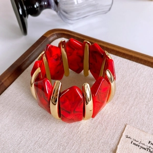 Detailed view of red marble resin blocks and gold metal segments on wide cuff bracelet