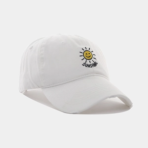 Close-up of sun smile embroidery and distressed brim on white cotton baseball cap