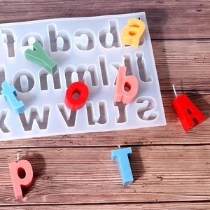Detailed view of silicone mold for DIY alphabet candles on a textured wood background
