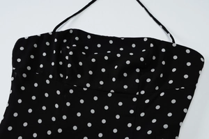 Detail of black polka dot strapless dress with thin neck straps and structured bodice