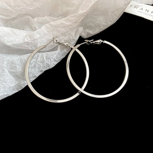 Detailed view of silver twisted geometric hoop earrings on black and white surface