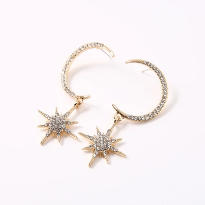 Macro detail of golden star and moon drop earrings featuring sparkling crystal pavé