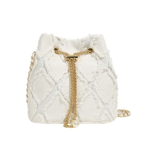 Close-up of denim bucket bag with diamond quilted pattern and pearl drawstring detail