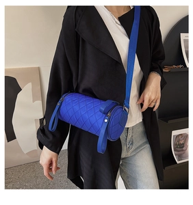 Quilted cylindrical crossbody bag in Klein Blue with wide shoulder strap on model