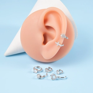 Detailed macro view of assorted zircon butterfly and cross stud earrings set in silver finish