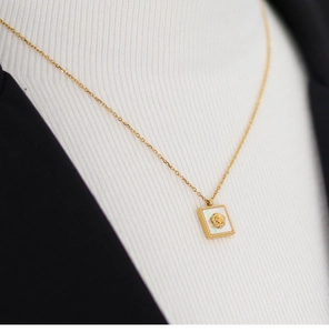 Detailed view of an 18K gold plated square rose necklace with white shell inlay