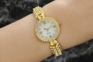 Detailed macro view of a gold quartz watch with sparkling rhinestones and roman numerals