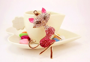 Close-up of a pink rhinestone-studded cat keychain charm on a white decorative plate