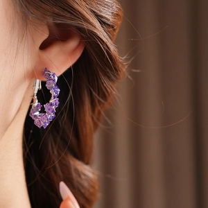 Close-up of elegant purple zircon hoop earrings with vintage crystal details on a model