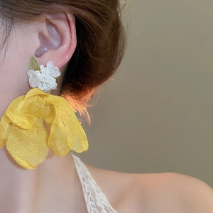 Close-up of model wearing vibrant yellow organza flower earrings with white bead details
