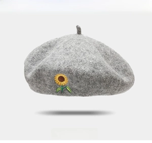 Close-up of sunflower embroidery on gray wool beret showing soft fabric texture
