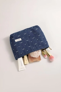 Detailed view of denim makeup bag with white bow embroidery and gold metal zipper