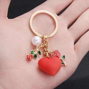 Sweet heart and rose pearl pendant keychain accessory shown handheld in golden metal