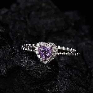 Macro detail of heart-shaped purple amethyst ring with sparkling halo on beaded silver band