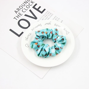 Detail of light blue Christmas scrunchie with snowman and tree patterns on a white plate