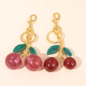 Detail of glittery cherry keychains in pink and red with golden lobster clasps