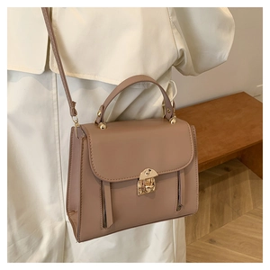 Detail of nude pink square bag showing golden twist lock and twin zipper accents