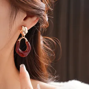 Retro amber resin earrings with golden metal buckle worn on model for a luxury look