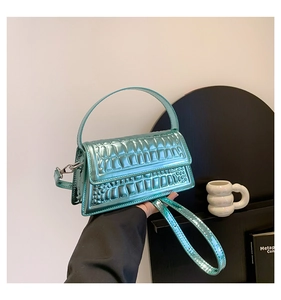 Detailed macro view of mint green glossy faux crocodile leather texture on handbag