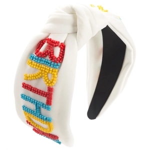 Détail de broderie en perles colorées BIRTHDAY sur un serre-tête noué blanc