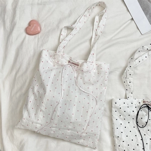 Detail of white canvas tote bags with heart patterns and decorative ribbon bow ties